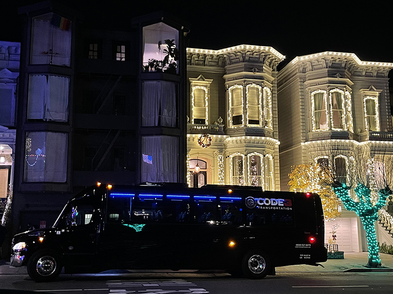 37 passenger executive sprinter with the logo for Code 3 Transportation is parked in front of a two-story home fully decorated with white holiday lights in the Bay Area